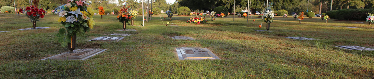 ground burial at Pinewood Memorial park with bronze grave markers and flowers